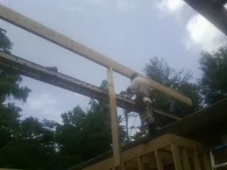 Carpenter setting a ridge beam over a new addition frame — Ice Dam Removal by Roofing Brothers in Longs